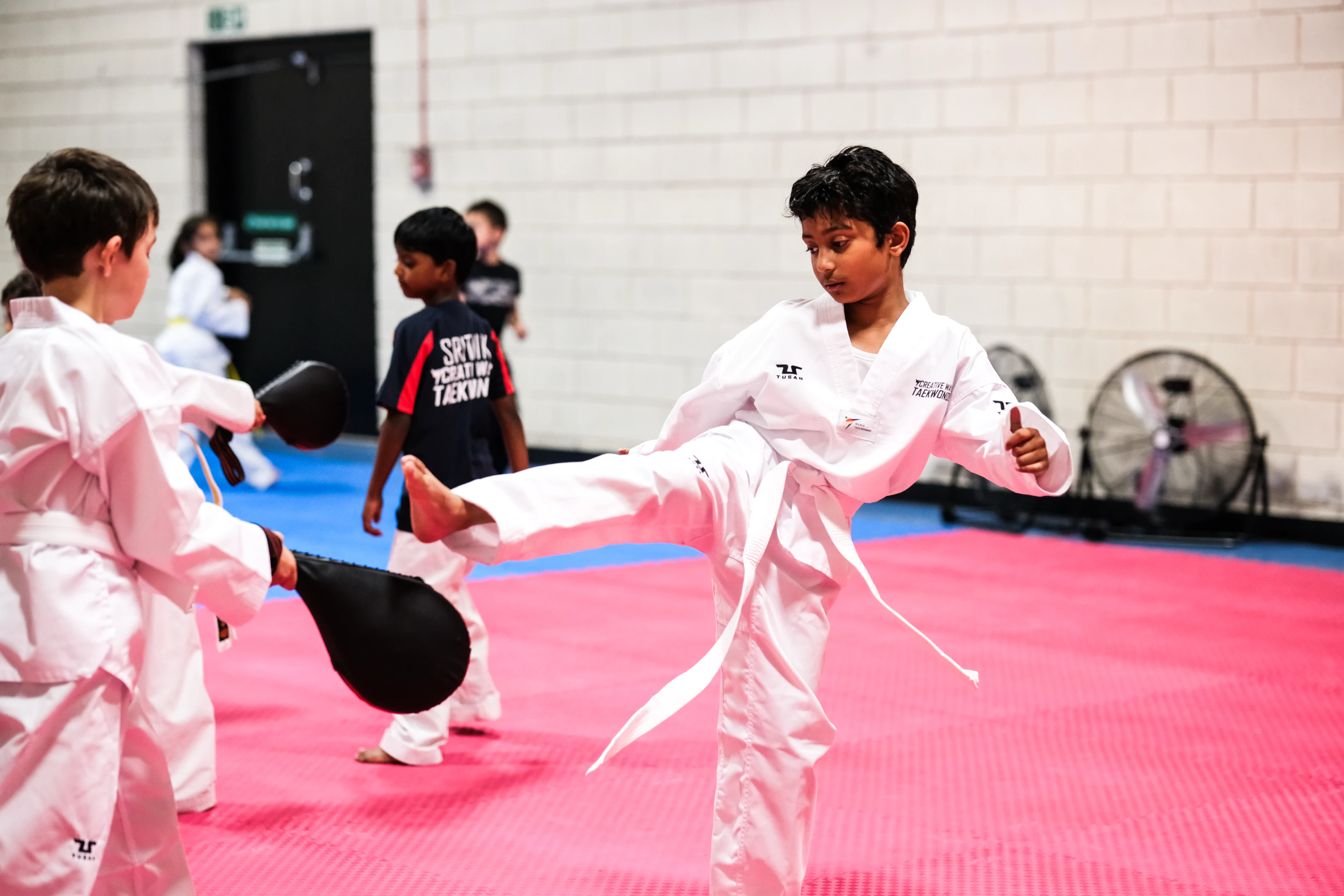Children practising pad kicks during a Creative Ways Taekwondo class