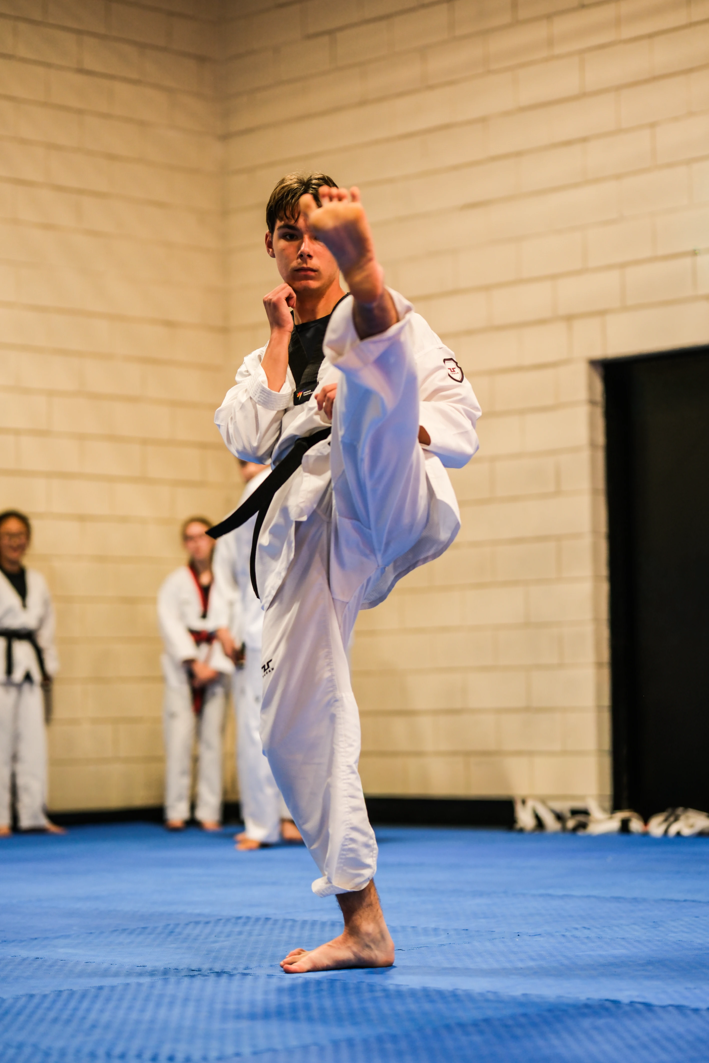 Teen student practising a controlled front kick during class